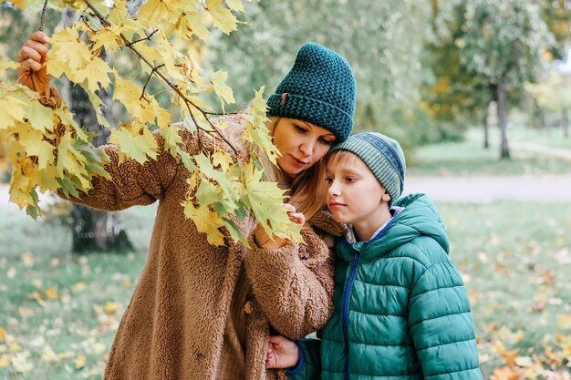 Famiglia felice madre e figlio che giocano e ridono durante la passeggiata autunnale