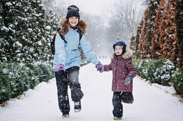 Famiglia felice madre figlio e gatto nello zaino che cammina sul vicolo nevoso nella natura nevosa invernale