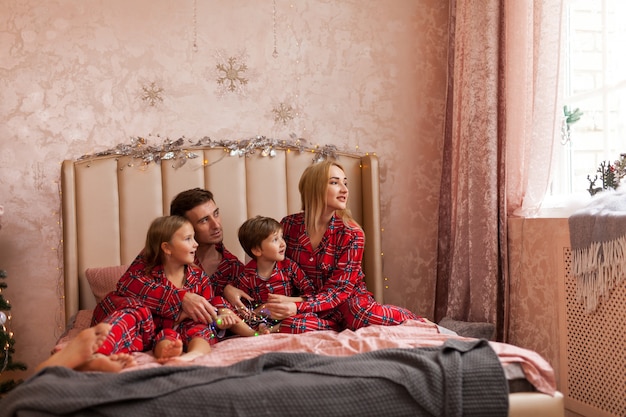Famiglia felice madre padre e bambini sulla mattina di Natale a letto in pigiama