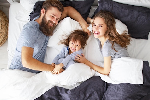 Famiglia felice madre padre e figlio a letto