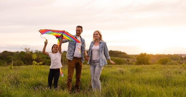 Famiglia felice: madre, padre, figlia sulla natura al tramonto.