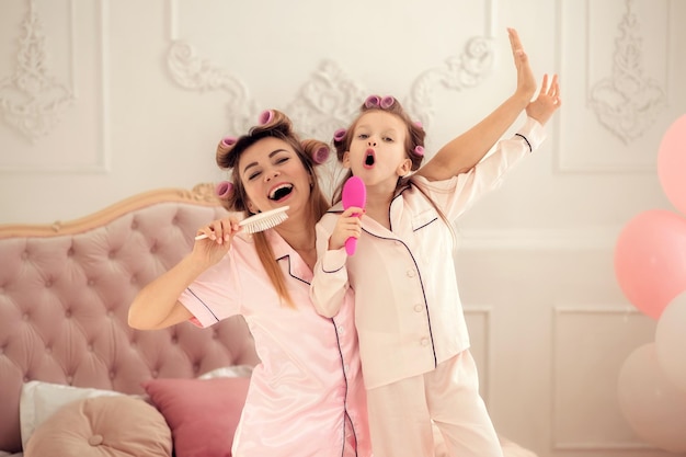 Famiglia felice mamma e figlia che trascorrono del tempo insieme a casa cantando in un pettine divertendosi