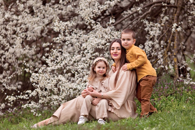 Famiglia felice, mamma incinta, figlia e figlio sullo sfondo di alberi in fiore.