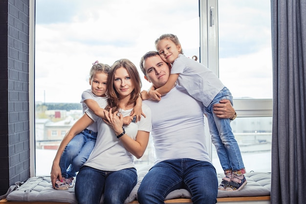 Famiglia felice mamma, papà e due sorelle gemelle ragazze a casa sullo sfondo della finestra.