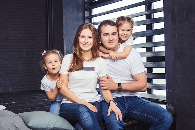 Famiglia felice mamma, papà e due sorelle gemelle ragazze a casa sullo sfondo della finestra.