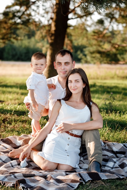 Famiglia felice mamma papà e figlio bambino felici nella natura trascorrere del tempo insieme in giornata di sole estivo.