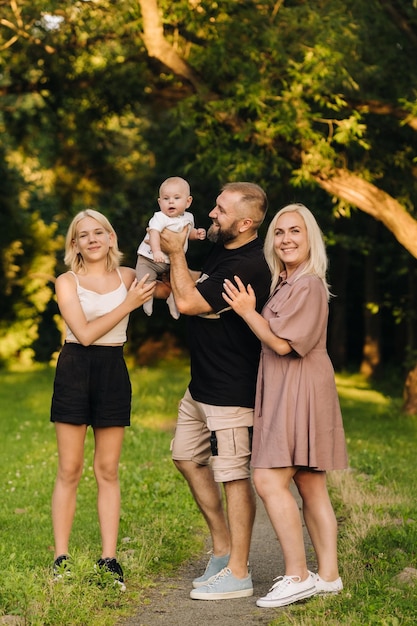 Famiglia felice nel parco di quattro persone in estate nel parco in natura