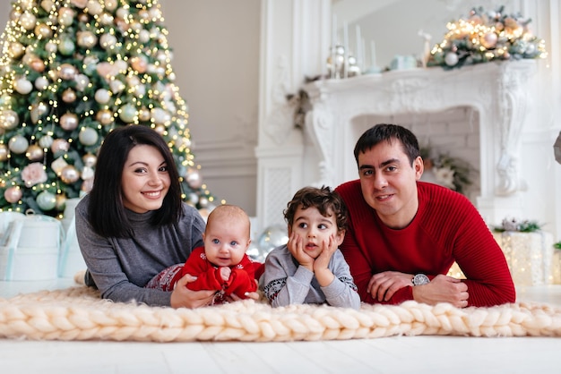 Famiglia felice nell'interno di Capodanno vicino all'albero di Natale Mamma papà figlio e figlia