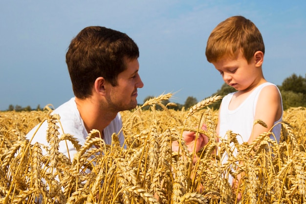 Famiglia felice Padre e figlio sul campo di grano Il maschio mostra la spiga di grano del ragazzo