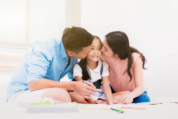 Famiglia felice padre, madre e bambina sul letto a casa