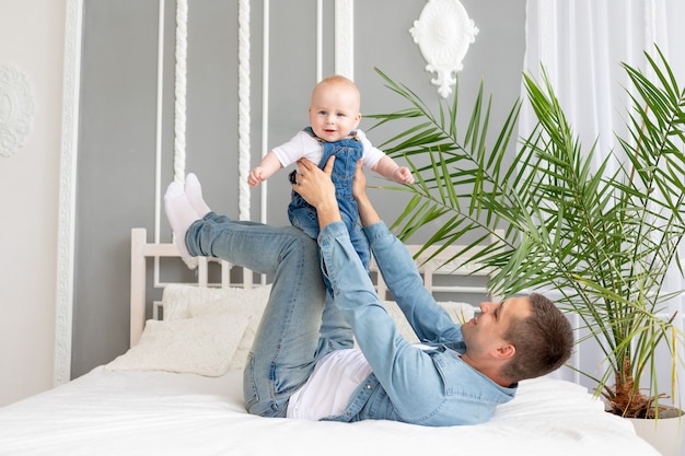 famiglia felice papà e bambino giocano e si coccolano sul letto