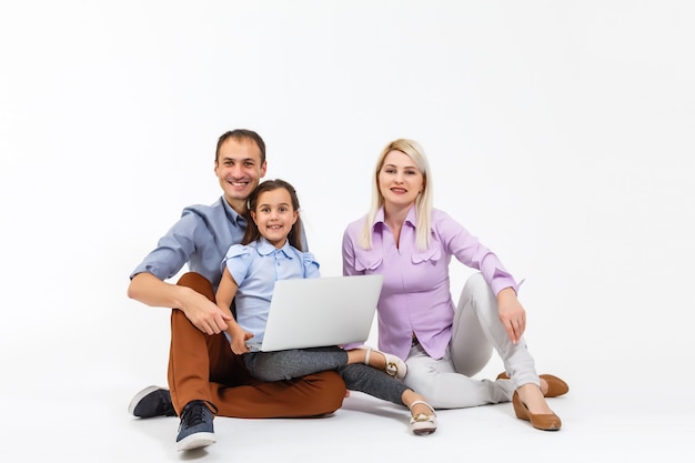 Famiglia felice sdraiata sul pavimento mentre naviga su internet online con il laptop, isolato su bianco