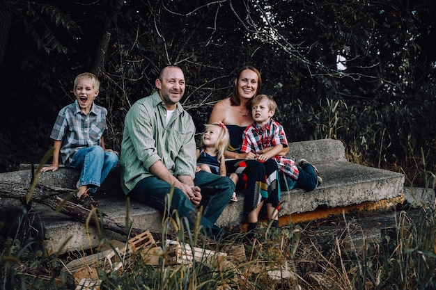 Famiglia felice seduta su un sedile di pietra contro gli alberi
