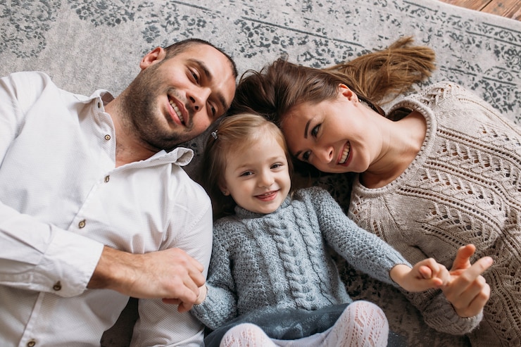 Famiglia felice sorridente a casa sdraiato sul pavimento