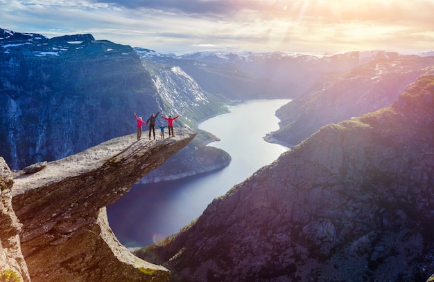 Famiglia felice su Trolltunga - Vista sulla Norvegia Paesaggio di montagna al tramonto Da Trolltunga - La lingua del Troll a Odda, Lago Ringedalsvatnet, Norvegia.