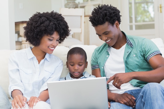 Famiglia felice sul divano con il portatile