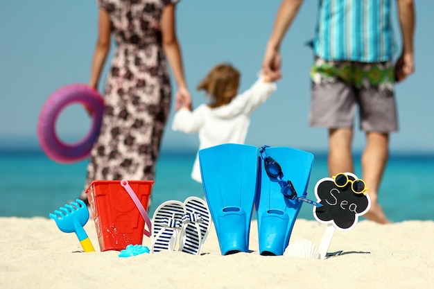 Famiglia felice sulla spiaggia con pinne e giocattoli