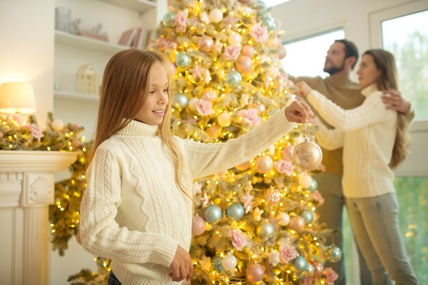 Famiglia felice sveglia che decora l'albero di Natale e si sente bene