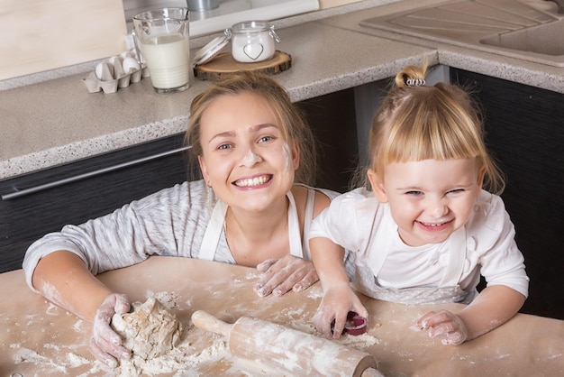 Famiglia felice Una figlia minuscola trascorre del tempo con sua madre in cucina a cuocere i biscotti