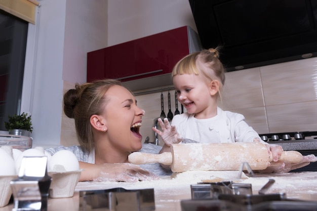 Famiglia felice Una figlia minuscola trascorre del tempo con sua madre in cucina a cuocere i biscotti