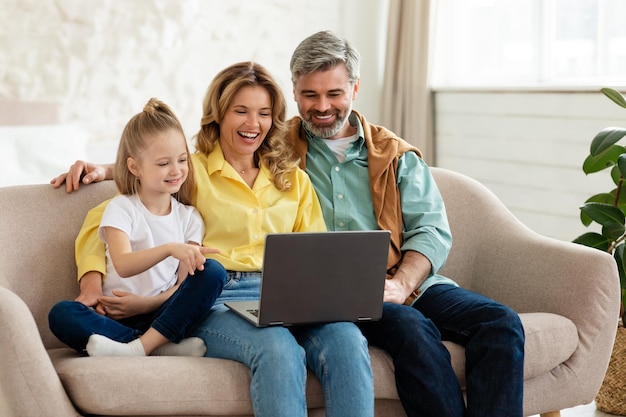 Famiglia felice utilizzando il computer portatile che naviga in Internet insieme a casa