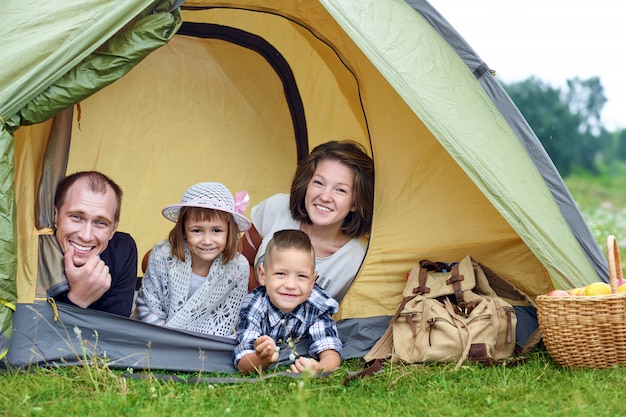 Famiglia Genitori e due bambini nella tenda da campo. Felice madre, padre, figlio e figlia in vacanza estiva