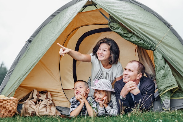 Famiglia Genitori e due bambini nella tenda del campo. Felice madre, padre, figlio e figlia in vacanza estiva. Mamma che mostra qualcosa in lontananza