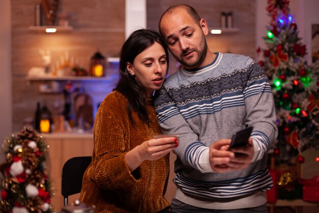 Famiglia gioiosa che fa shopping online utilizzando la carta di credito che paga il regalo di Natale regalo