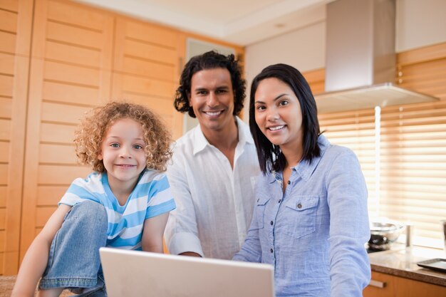 Famiglia gioiosa che naviga in internet in cucina insieme