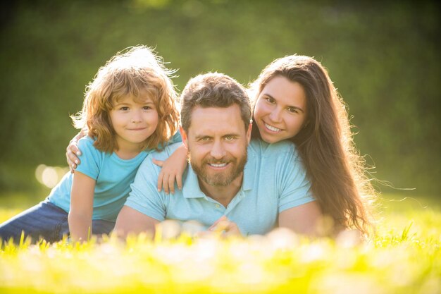 Famiglia giorno amicizia padre madre e figlio sul parco verde erba famiglia amichevole divertendosi in estate ritratto di genitori con bambino ragazzo mamma papà e figlio amore rilassarsi insieme adozione e beneficenza