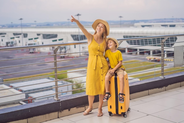 Famiglia in aeroporto prima del volo Madre e figlio in attesa di imbarcarsi al gate di partenza del moderno terminal internazionale Viaggiare e volare con i bambini Mamma con bambino che si imbarca sull'aereo giallo aspetto familiare