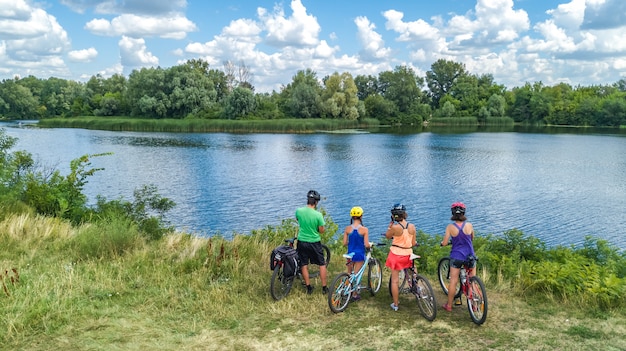 Famiglia in bici in bicicletta all'aperto, genitori e bambini in bicicletta, vista aerea superiore della famiglia felice