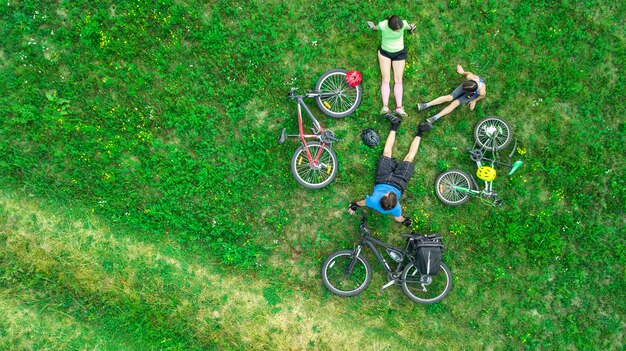 Famiglia in bicicletta in bici all'aperto vista aerea dall'alto, felici genitori attivi con bambino divertirsi e rilassarsi sull'erba, sport di famiglia e fitness durante il fine settimana