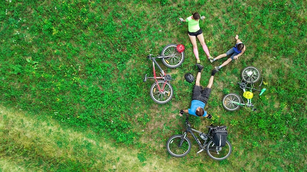 Famiglia in bicicletta in bicicletta vista aerea dall'alto, i genitori attivi felici con il bambino si divertono e si rilassano sull'erba, lo sport familiare e il fitness nel fine settimana