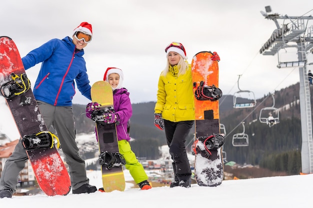 Famiglia in cappelli di Babbo Natale e snowboard