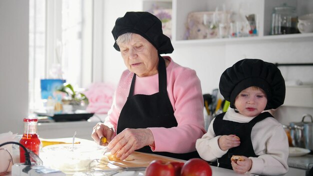 Famiglia in cucina a fare i dolci Una donna anziana che taglia la banana