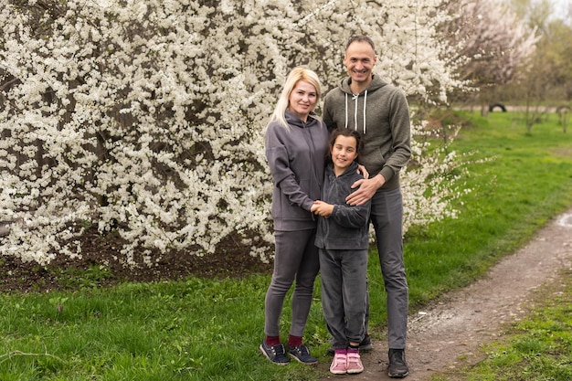 Famiglia in giardino fiorito con alberi.