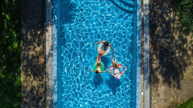 Famiglia in piscina vista aerea del drone dall'alto, madre e bambini felici nuotano su ciambelle gonfiabili e si divertono in acqua in vacanza con la famiglia, vacanze tropicali in resort
