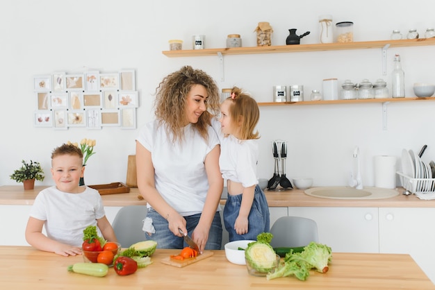 Famiglia in una cucina. Bella madre con bambini. Signora in camicetta bianca.