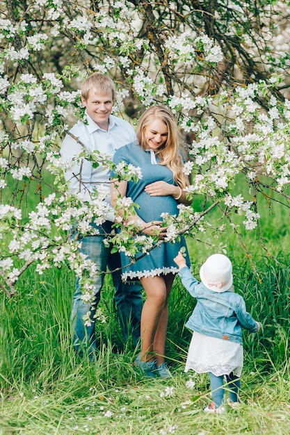 Famiglia incinta felice nel giardino fiorito