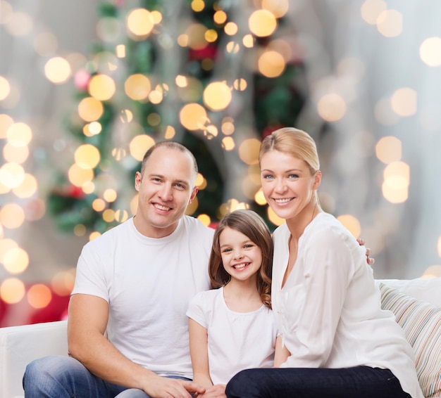 famiglia, infanzia, vacanze e persone - madre, padre e bambina sorridenti sullo sfondo delle luci dell'albero di Natale
