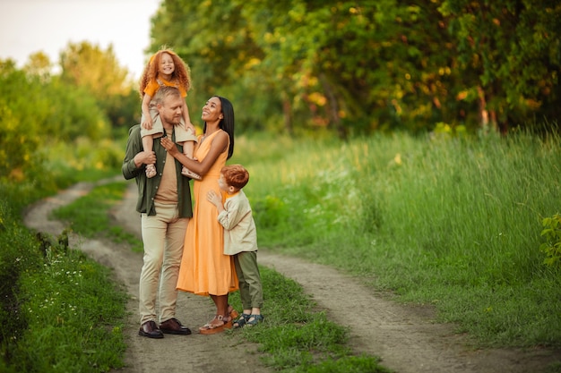 Famiglia internazionale felice in una passeggiata estiva nel parco.