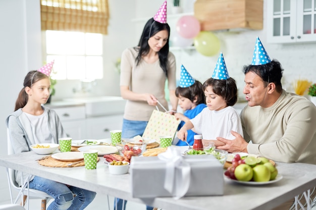 Famiglia ispanica felice che cena mentre festeggia il compleanno insieme a casa. Genitorialità, concetto di celebrazione. Messa a fuoco selettiva