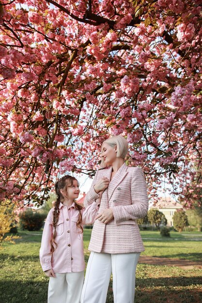 Famiglia madre e bambini in una strada cittadina primaverile con fiori di ciliegio giapponesi rosa