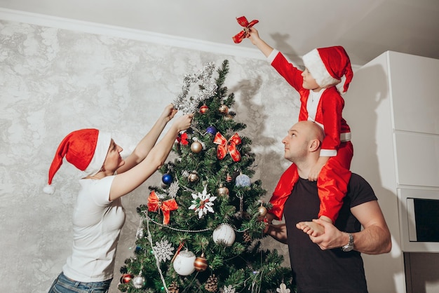 Famiglia mamma papà e figlio decorano l'albero di Natale dall'alto