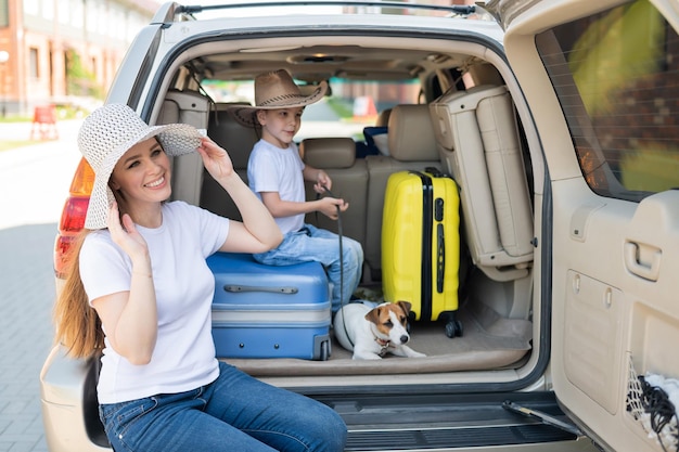 Famiglia monoparentale europea e cucciolo di Jack Russell viaggiano in macchina Bambino con sua madre e un cagnolino sono seduti nel bagagliaio e vanno in vacanza estiva Viaggio di famiglia indipendente con un bambino