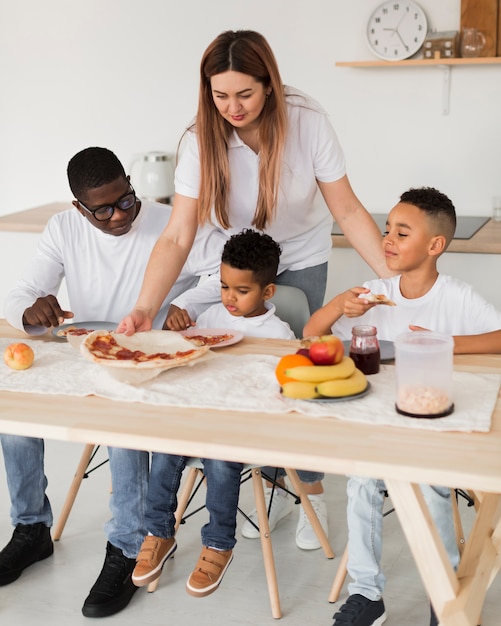 Famiglia multiculturale che mangia pizza