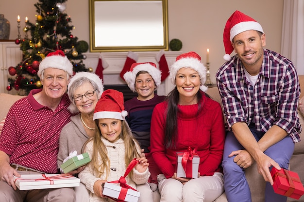 Famiglia multigenerazionale che indossa cappelli di santa sul divano