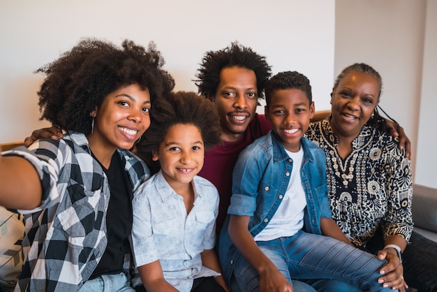 Famiglia multigenerazionale che prende selfie a casa.