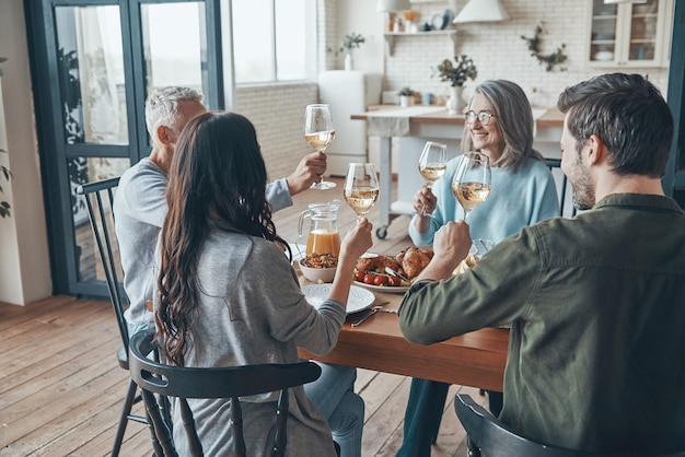 Famiglia multigenerazionale che si brinda a vicenda e sorride mentre cena insieme